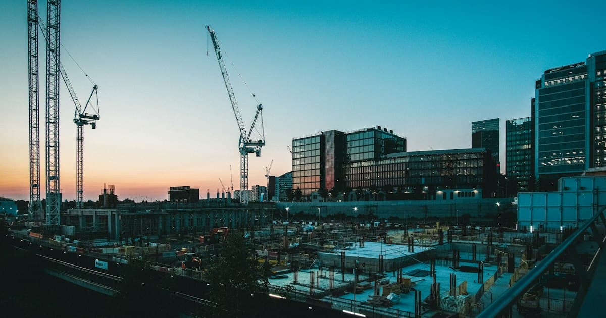 夕日に照らされた建設現場と複数のクレーン